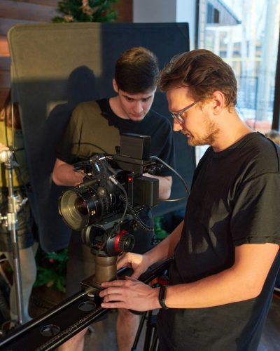 young-videographer-and-his-assistant-adjusting-options-of-video-camera.jpg